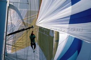 Bowman at end of spinnaker pole preparing to blow the tack of the sail