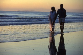 Couple walk along the shore at sunset