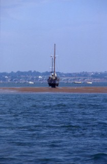Yacht stranded on sand bank at low tide