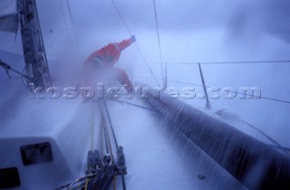 Crew member on racing yacht holds on to rigging in storm conditions
