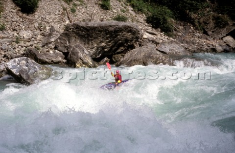 A conoeist paddles into fierce rapids