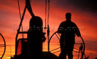 Silhouette of helmsman onboard racing yacht at sunset