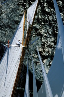 Sailor cimbing up mast of classic yacht