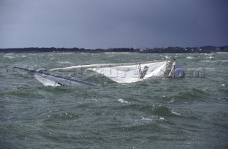Supported by its bouyancy, a J24 yacht sinking under sail after a broach