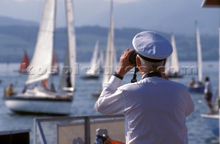 Naval Officer observing and looking out at passing yachts from the bridge