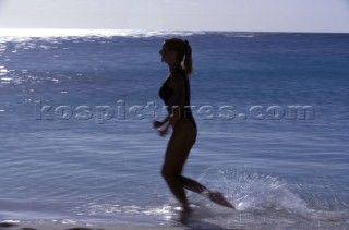 Silhouette of woman runing along shore