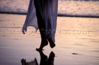 Reflection of womans feet on wet sand