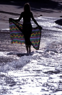Silhouette of woman with sarong on beach at sunset
