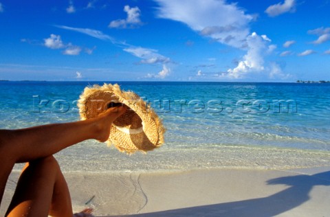 Model sits under umbrella on tropical beach