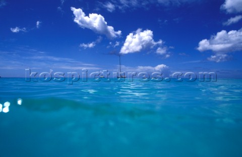 Above and below  surface of the Caribbean sea with anchored yacht in distance