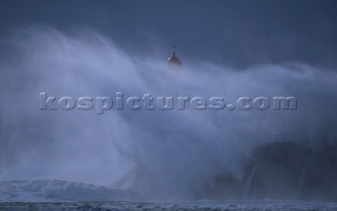 A lighthouse is battered by huge waves in a rough sea