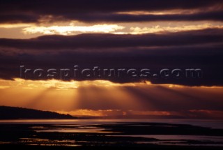 Sun rays behind cloud in the Severn estuary, UK.