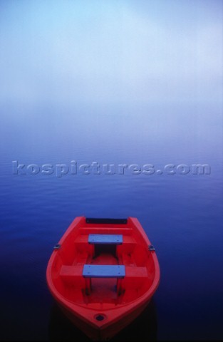 Red boat floating on Hawkesbury river on a misty morning light