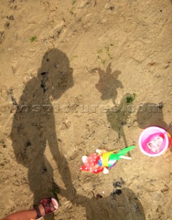 Silhouette and shadow of little girl playing in the sand on the beach
