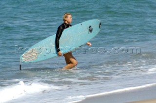Female surfer walking out of sea with long board under her arm