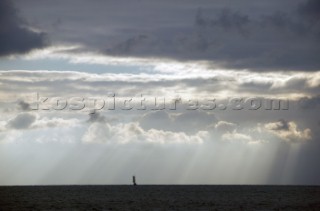 Lone classic sailing yacht in solitude sails into a stormy sky with clouds at sea off Key West, Florida, USA. Key West