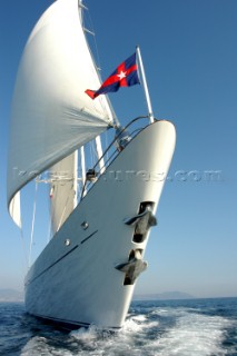 Bow of sailing superyacht with flag and anchor stowed