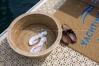 Sandals and deck shoes by a basket and welcome mat on the dock