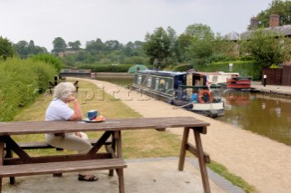 Woman watching narrow boats on the Llangollen canal at Ellesmere,Shropshire,UK.