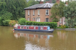 People on narrow boat passing house  on the Llangollen canal at Ellesmere,Shropshire,England.