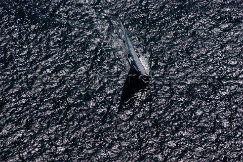 Aerial shot of yacht sailing across a black textured sea