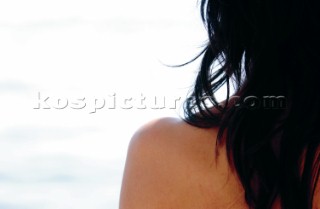 Close up of bare left shoulder of lady with long black hair