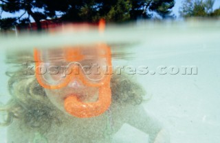 Underwater shot of lady snorkelling wearing bright orange goggles and snorkle