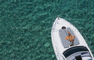 A girl in bikini sunbathes on the foredeck of power boat