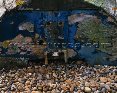 Weathered paint and wood with Lichen growth on EDs boat  upturned on the pebbles of Chesil beach in 