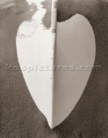 Heart shape formed from drifting sand around bow prow of an upturned boat hull  Sand has texture fro