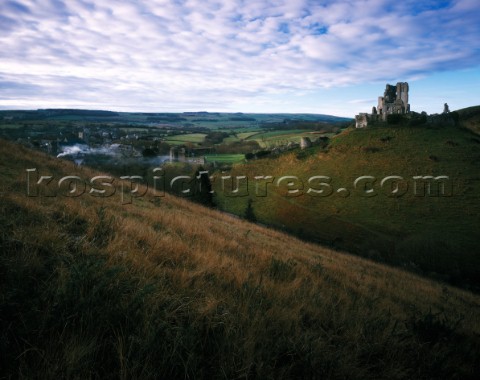 Soft dawn light yields subtle winter colours on the hillsides castle ruins and village of Corfe Smok