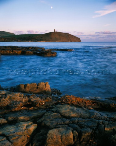 The moon has risen early and is climbing to a position above Clavells Tower Kimmeridge Devon on Engl