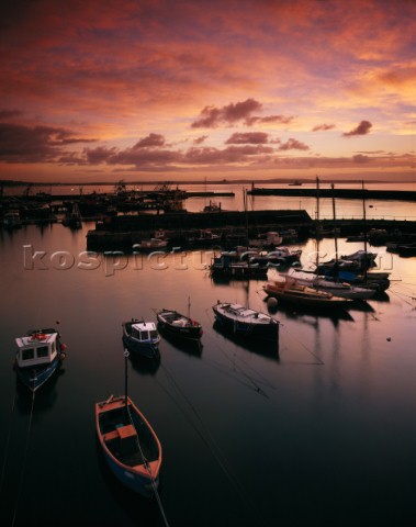 Soft stronglycoloured dawn light floods into Newlyn Harbour and Mounts Bay in the distance A wide va