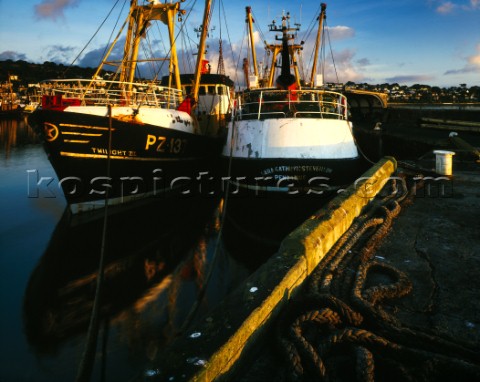 Warm early sun falls on these two trawlers alongside Newlyn harbour