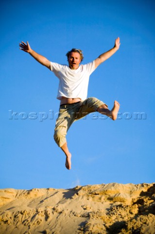 Man jumping off giant sand dunes on a sandy beach in Tarifa Spain near Gibraltar Model released
