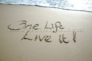 One Life - Live it sign writing message on a sandy beach in Tarifa, Spain, near Gibraltar.