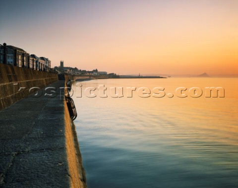 A calm and atmospheric sunrise at the Promenade in Penzance with the Jubilee Pool and St Michaels Mo