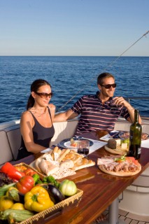 Lifestyle couple dining and eating dinner or lunch onboard a Vicem 72 classic motor yacht Model Released.