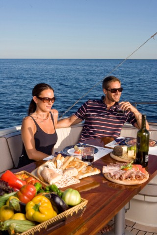 Lifestyle couple dining and eating dinner or lunch onboard a Vicem 72 classic motor yacht Model Rele