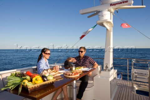 Lifestyle couple dining and eating dinner or lunch onboard a Vicem 72 classic motor yacht Model Rele