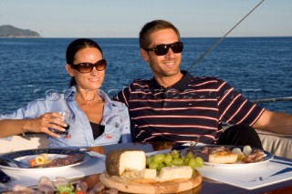 Lifestyle couple dining and eating dinner or lunch onboard a Vicem 72 classic motor yacht Model Released.