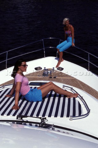 Two female models sitting on bow of Fairline powerboat