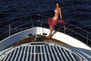 Female model in bikini sitting on bow of Fairline powerboat