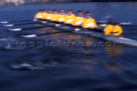A team of rowers wearing yellow uniform clothing  in a skull on the River Thames