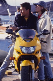 Man and woman on motorbike by yachts on the dock
