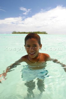 A young boy plays off Honeymoon Island, Cook Islands, South Pacific.