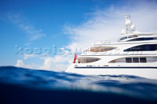 Side view of a superyacht in the mediterranean sea. Woman standing on deck  and leaning on railing looking at view