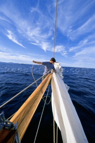 The bowman on board the classic schooner  Wendameen furls the jib at the end of the bowsprit after a
