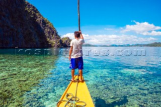 Filipino boatman navigating through a shallow reef at Hidden Lagoon, Coron Island, Palawan, Philippines