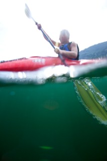 Over under water view of Patrick Orton paddling a sea kayak in Lake Pend Oreille near Sandpoint, Idaho